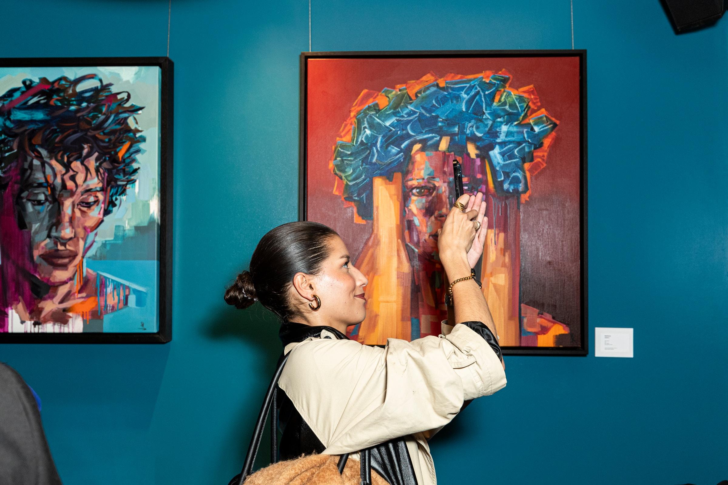Visitor looking closely at a colourful portrait painting in a teal room at COYA City