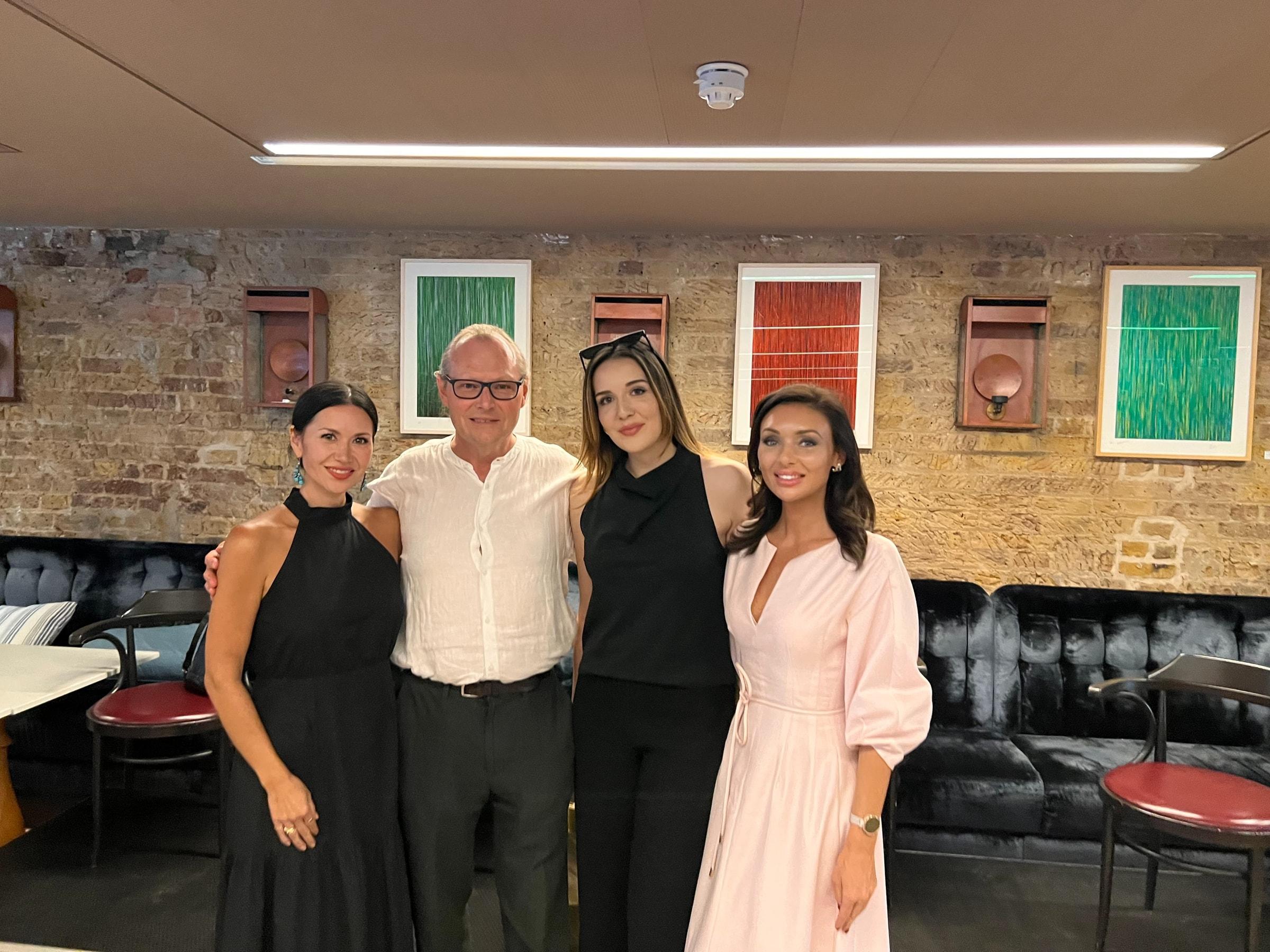 Four people standing together in a brick-walled room at The Conduit Members’ Club after a panel talk