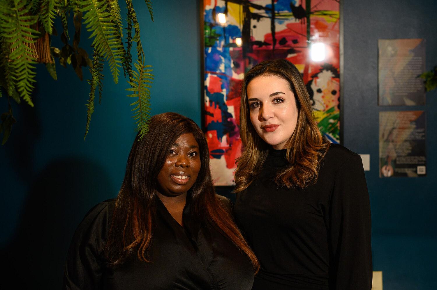 Two women posing in front of colourful paintings at COYA City