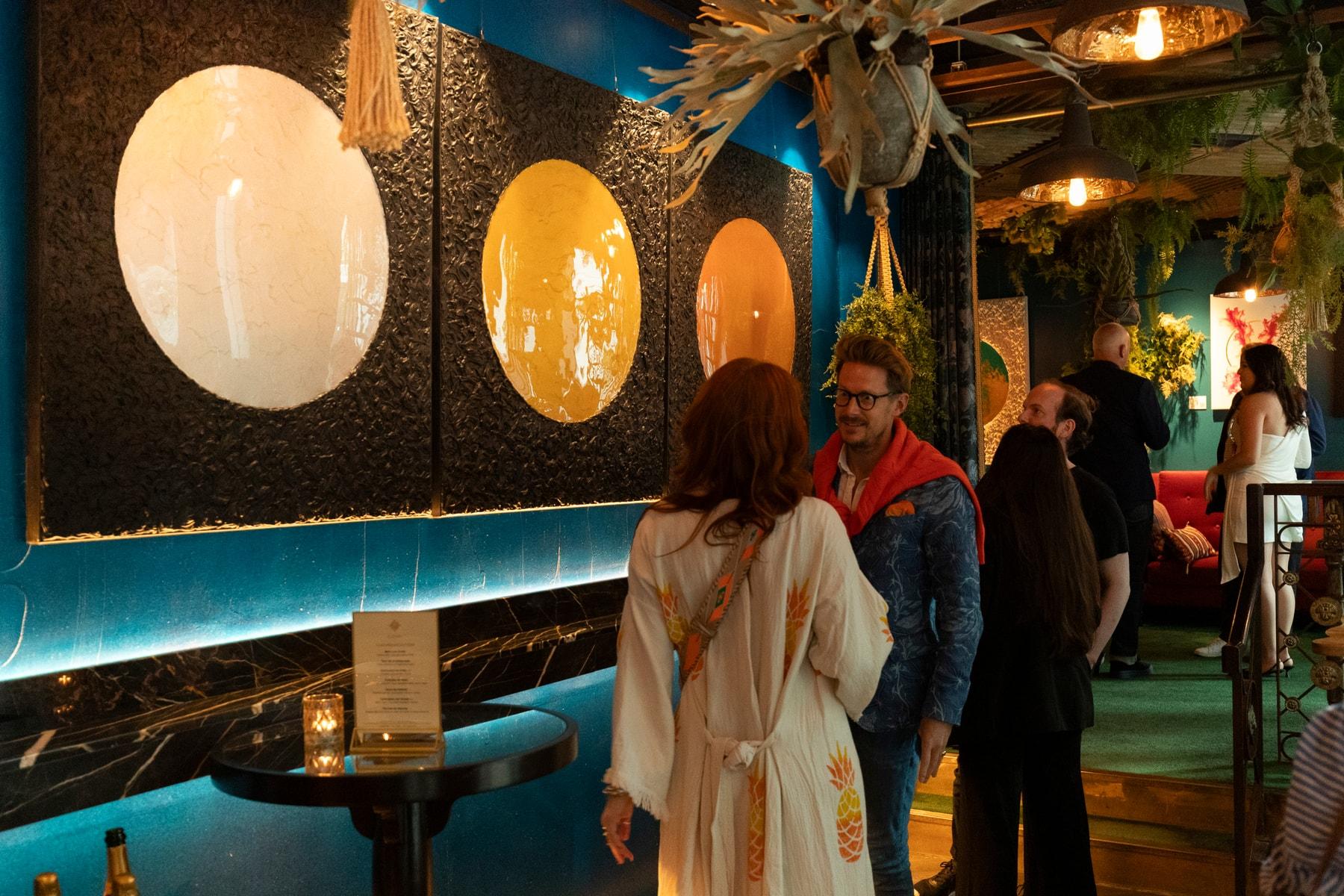 Guests viewing Gavin Johnson’s artworks on a dark wall at COYA City