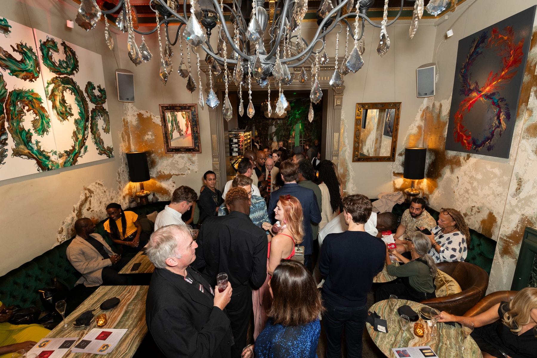 Guests gathered at a private view at COYA Mayfair, with green sculptural wall pieces and paintings behind them